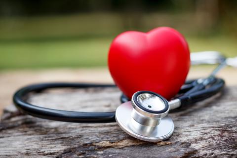 Red heart and a stethoscope on wooden background.