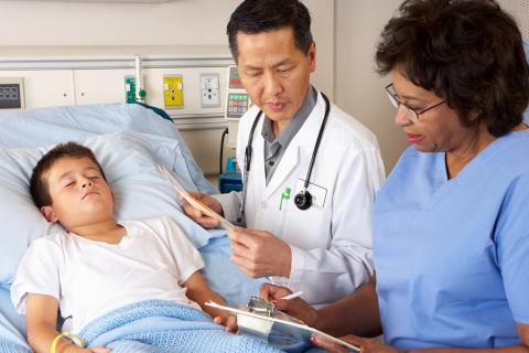 Doctor and nurse visiting child patient on hospital ward