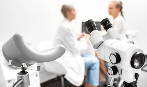 Colposcopy, examination of a cervix. Colposcope close-up, in the background a gynecologist and a female patient