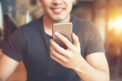 Man smiling while looking at his smartphone