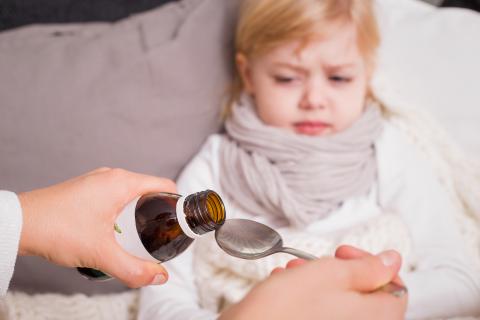 Unhappy little girl being fed medicine