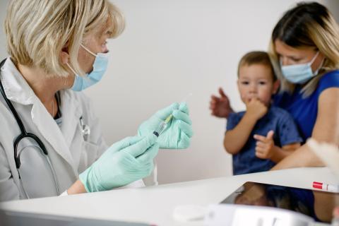 Parent with their child at a doctor's office, preparing for a vaccination