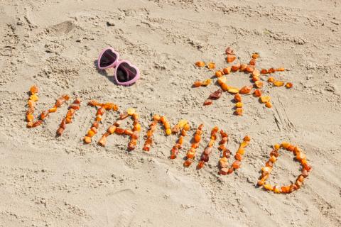 Sunglasses, inscription vitamin D and shape of sun on sand at beach, summer time and healthy lifestyle