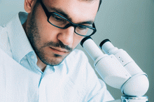 A scientist looks through a microscope