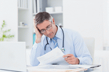 A doctor does paperwork at a desk
