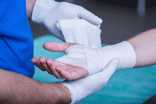A doctor wraps a bandage around a patient's hand