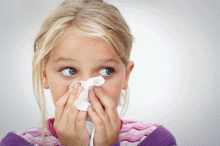 A child sneezes into a tissue
