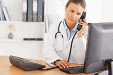A doctor works on a computer while talking on the phone