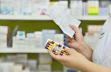 A pharmacist takes a package of antibiotics off of a shelf