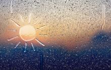 A window covered in raindrops; the shape of a sun has been made within the water