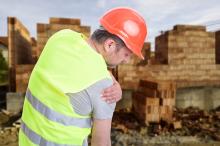 A construction worker holds his shoulder in pain