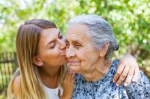 A girl kisses her grandmother on the cheek