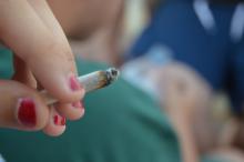 A teenager holds a joint