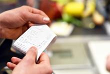 A pair of hands holding a receipt after payment in the supermarket