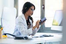 Doctor browsing on her smartphone at her desk