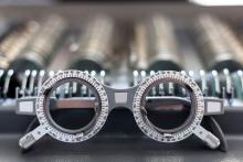 A pair of ophthalmologist test glasses in front of rows of lenses