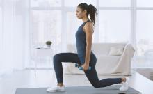 A woman does a lunge while holding hand weights