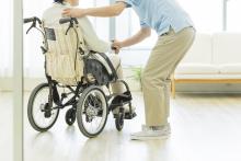 An aide assists a senior using a wheelchair