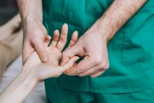 A doctor massages a patient’s hands