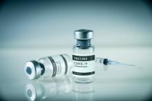 Two vials of COVID-19 vaccine and a syringe