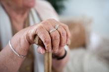A senior sits down, holding a cane