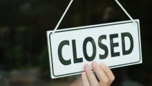 A sign in a storefront window is turned to "Closed"