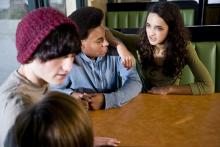 A group of young people sit at a table, talking