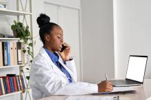 A doctor talks on the phone while working on her computer