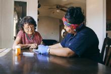An Indigenous health care worker consults with a patient in their home