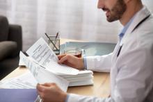 A doctor is reviewing a stack of medical reports.
