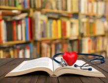 An open book with a stethoscope and a heart-shaped stress ball.