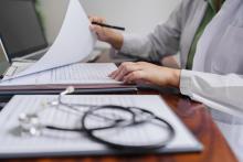 A doctor sits at a desk, filling out forms.