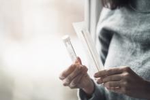 A woman holds a swab and test tube from a sample collection kit.