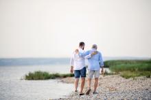 A father and son walk together on a rocky shore.