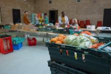Bins of food at a food bank, with blurred people in the background.
