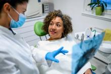 A dentist and patient look at and discuss X-rays.