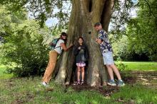 Dr Chahal with her family standing in front of a large tree.