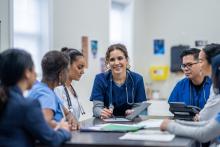 A group of doctors sit at a boardroom table.