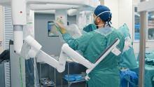 A surgeon sets up robotic surgery equipment.