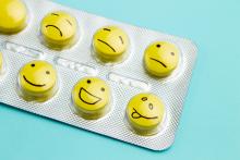Yellow pills and funny faces in a blister on a blue background. 