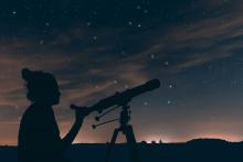 An astronomer looks at the night sky through a telescope