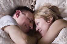 A couple is lying in bed together, snuggling