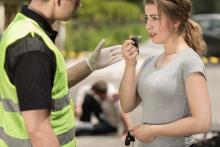 Woman being coaxed into taking a breathalyzer test