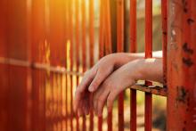 Female hands behind bars