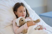 Young girl holding a teddy bear sleeping in a hospital