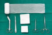 Surgical tools: scissors, gauze, bandage, pad, cramp, blade, knife on green surgical dress background