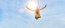 Woman on a swing with blue sky above her