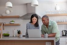 Couple conversing while looking at a laptop in their kitchen 