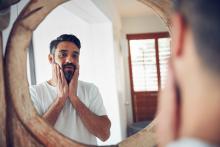 Man looking in the mirror, concerned about his appearance