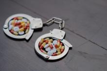 Handcuffs and pills. Selective focus - concept